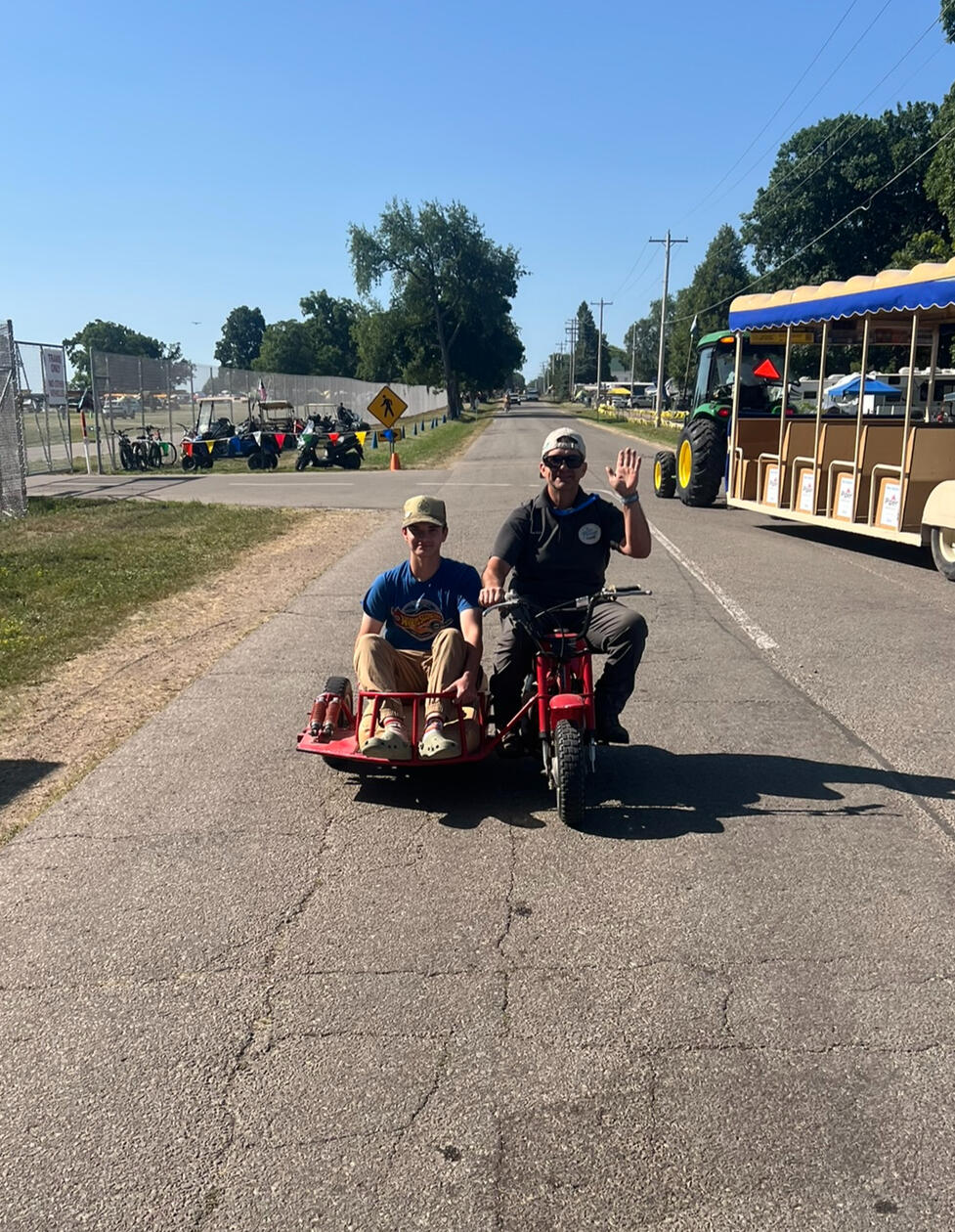 A weird little moped with a side car on its way into the show grounds