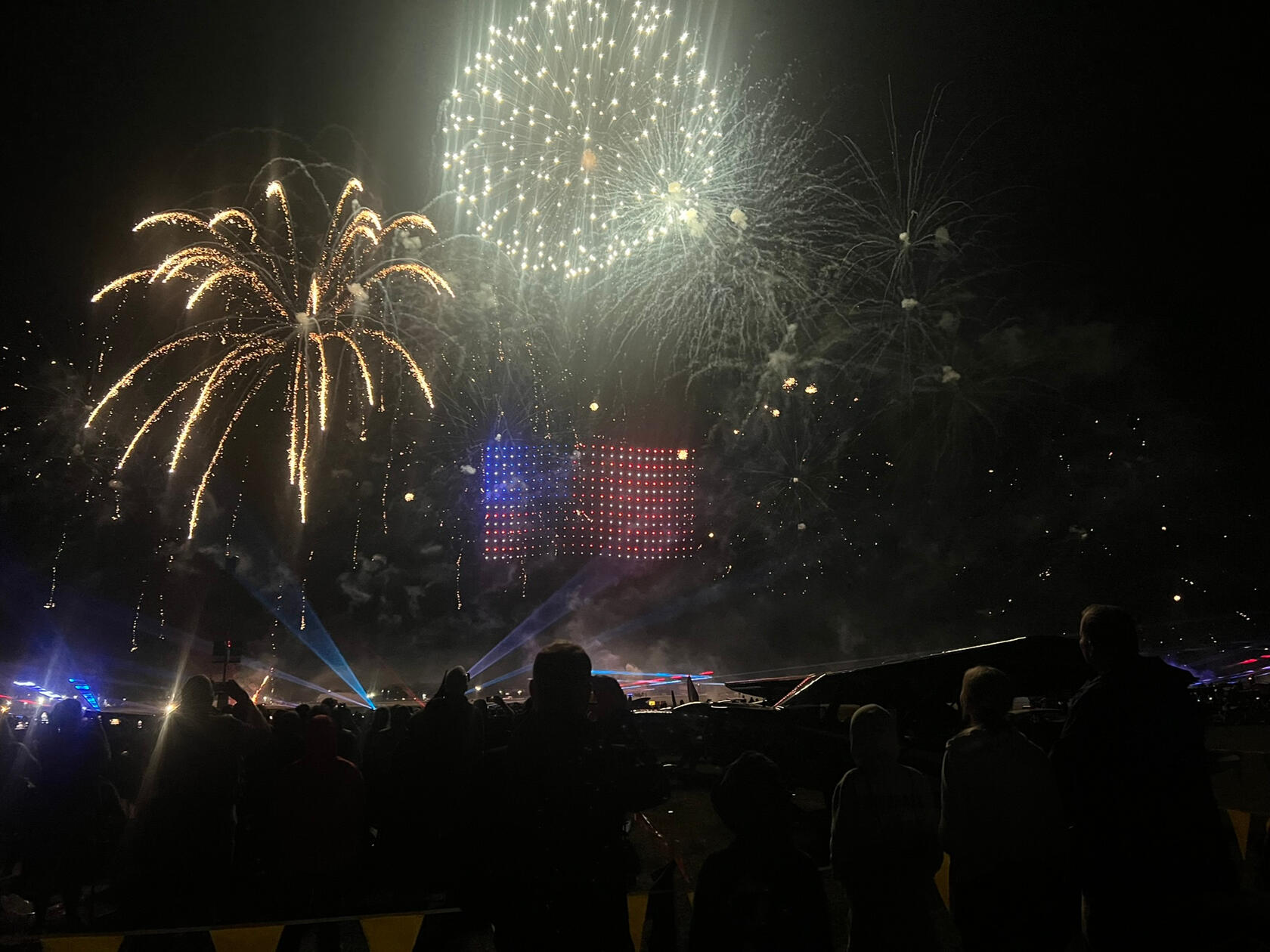Drones making an American flag in the sky, surrounded by fireworks